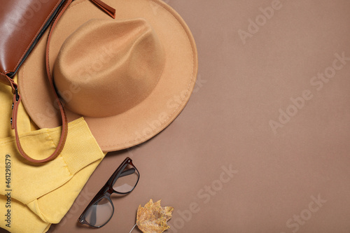 Flat lay composition with stylish hat on brown background, space for text