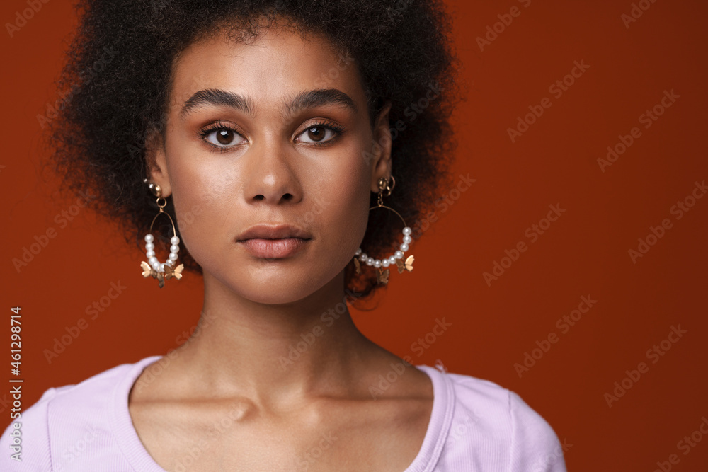 Black young woman in earrings posing and looking at camera