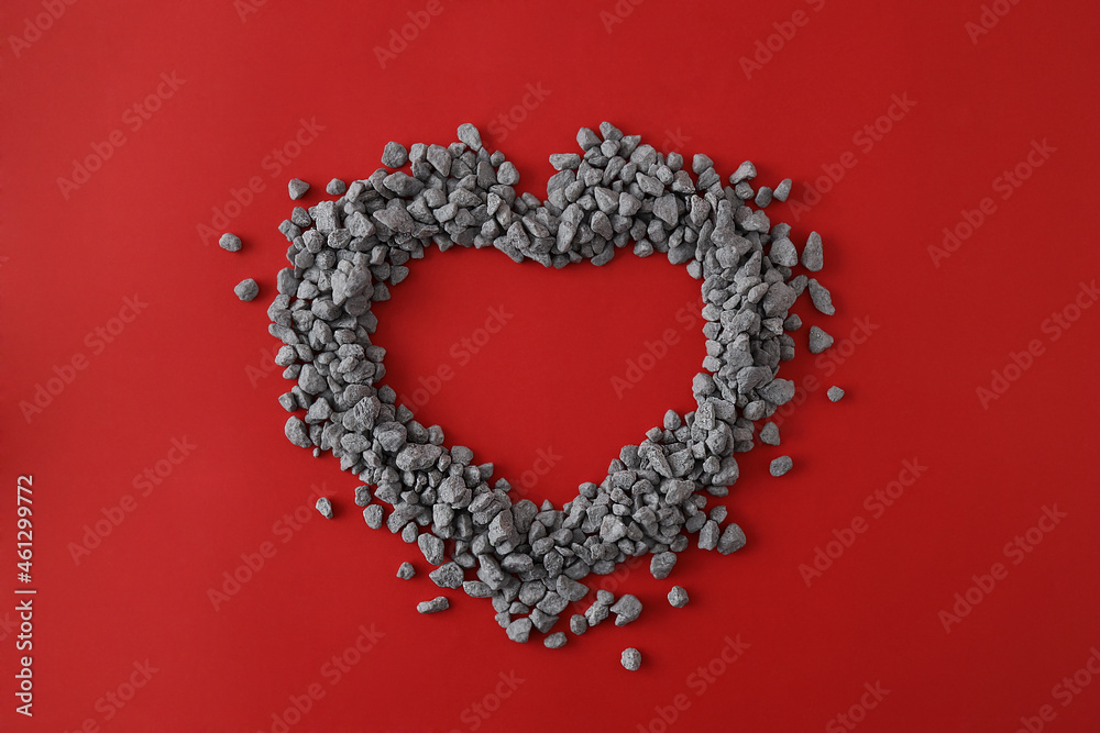 Top view of shape of heart made out of little pebbles on red background