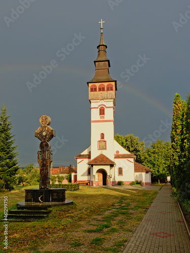  Sunlit Assumption church of against a dark sky with rainbow in Orastie, Romania  photo