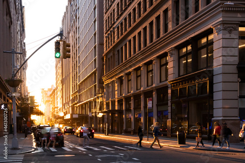 Busy intersection with crowds of people walking through an intersection on 5th Avenue in New York City with summer sunlight shining