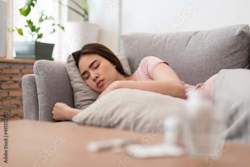 Young woman is sick, unwell, cold and sleep on the sofa. After taking medicine