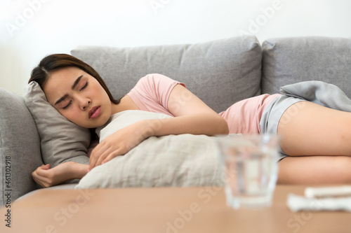 Young woman is sick, unwell, cold and sleep on the sofa. After taking medicine