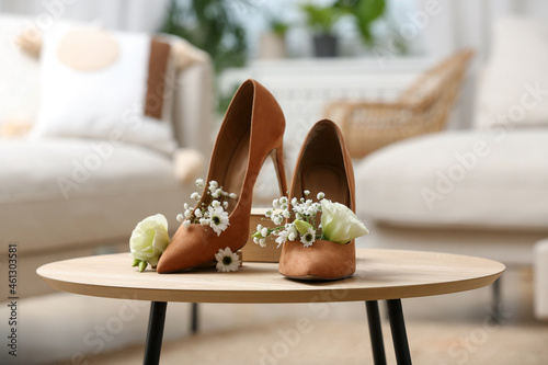 Women's shoes with beautiful flowers on table indoors photo