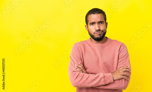 Young latin man isolated on yellow background feeling upset