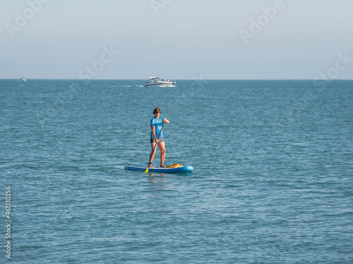 Paddle boarder. Sportsman paddling on stand up paddleboard. SUP surfing. Active lifestyle. Outdoor recreation. Vacation on seaside. © Konstantin Aksenov