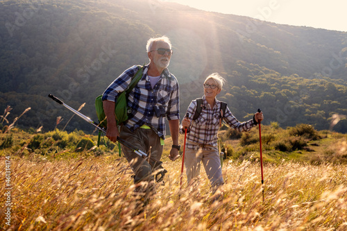 Mature couple walking in nature with backpack at the sunset at background