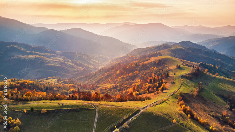 Beautiful mountain autumn landscape with meadow and colorful forest. Red, Yellow, Orange trees on hillsides.