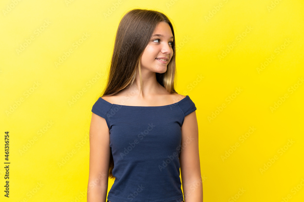 Little caucasian girl isolated on yellow background looking side Little caucasian girl isolated on yellow background looking side