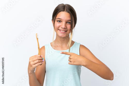 Little caucasian girl holding a toothbrush isolated on white background and pointing it