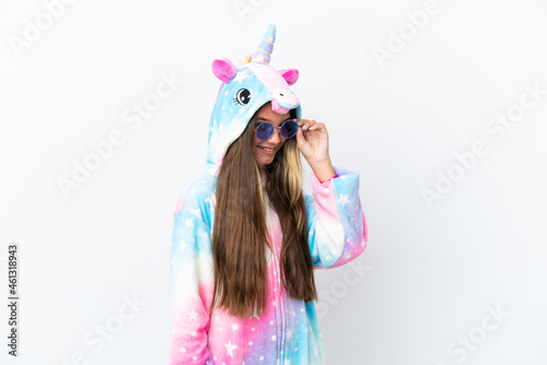 Little caucasian girl wearing unicorn pajama isolated on white background with glasses and happy