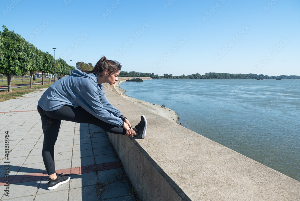 Young beautiful happy sporty fitness woman standing outdoor stretching her muscles preparing for jogging and running exercise while preparing for workout and training motivation for marathon Young beautiful happy sporty fitness woman standing outdoor stretching her muscles preparing for jogging and running exercise while preparing for workout and training motivation for marathon
