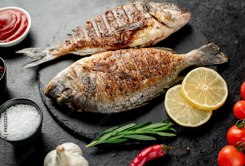 grilled dorado fish with lemon and rosemary on stone background grilled dorado fish with lemon and rosemary on stone background