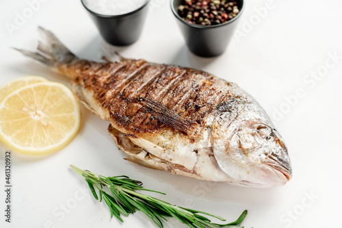 grilled dorado fish with lemon and rosemary on a white background, isolate