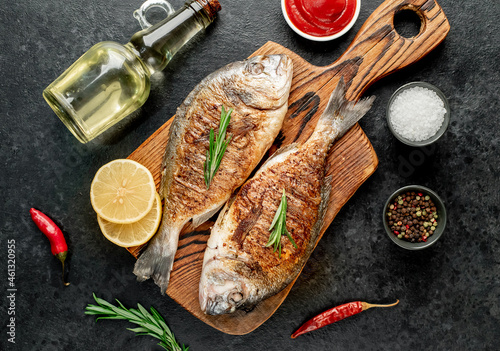 grilled dorado fish with lemon and rosemary on stone background