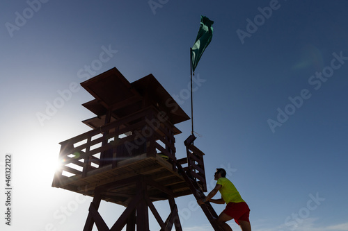 Lifeguard climbing on wooden observation tower