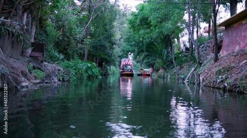 Traditional colorful trajinera surrounded by trees in Xochimilco lake