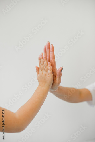 The child's palm touches the adult's palm.
Trust, friendship, love of generations.
Child and adult.
Support and support. Light photo, white background.