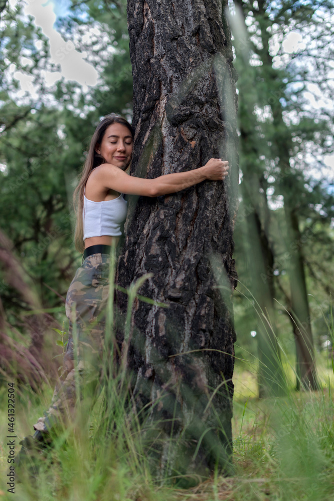 Peaceful woman hugging tree in forest Peaceful woman hugging tree in forest