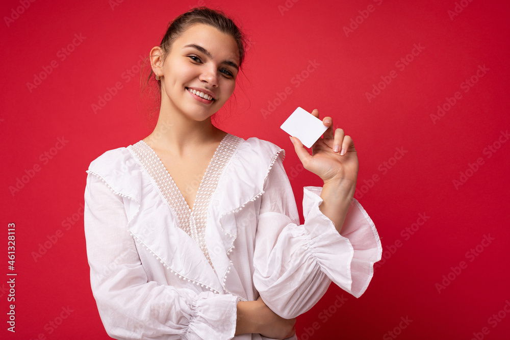 Portrait of young attractive caucasian hipster woman in trendy casual clothes. Sexy carefree female person posing isolated near red wall in studio. Positive model with natural makeup. Holding credit Portrait of young attractive caucasian hipster woman in trendy casual clothes. Sexy carefree female person posing isolated near red wall in studio. Positive model with natural makeup. Holding credit