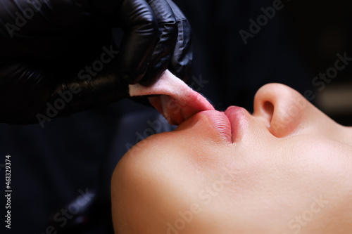 close-up the master erases the red pigments from the lips of the tattoo model with a sponge