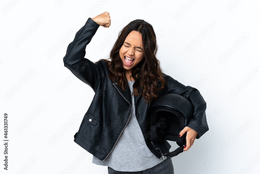 Young woman holding a motorcycle helmet over isolated white background celebrating a victory Young woman holding a motorcycle helmet over isolated white background celebrating a victory