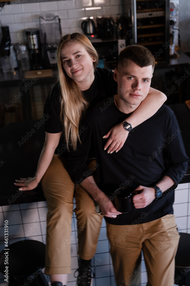 Fototapeta premium happy married couple in identical clothes family look - cafe owners or workers - in modern coffee shop. family business. loft cafe