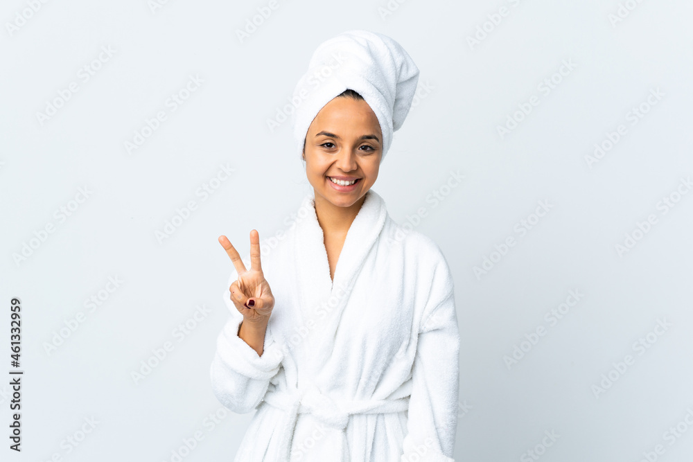 Young woman in bathrobe over isolated white background smiling and showing victory sign Young woman in bathrobe over isolated white background smiling and showing victory sign