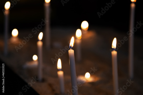 Candle light. Candles light in dark background. Candle flames in catholic church. Bokeh effect.