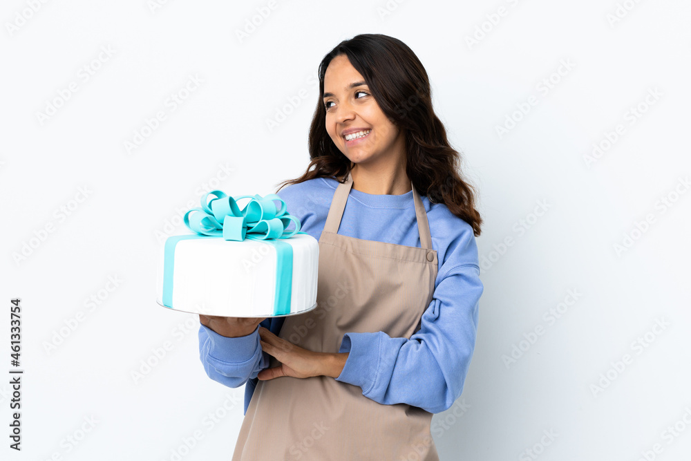 Pastry chef holding a big cake over isolated white background happy and smiling Pastry chef holding a big cake over isolated white background happy and smiling