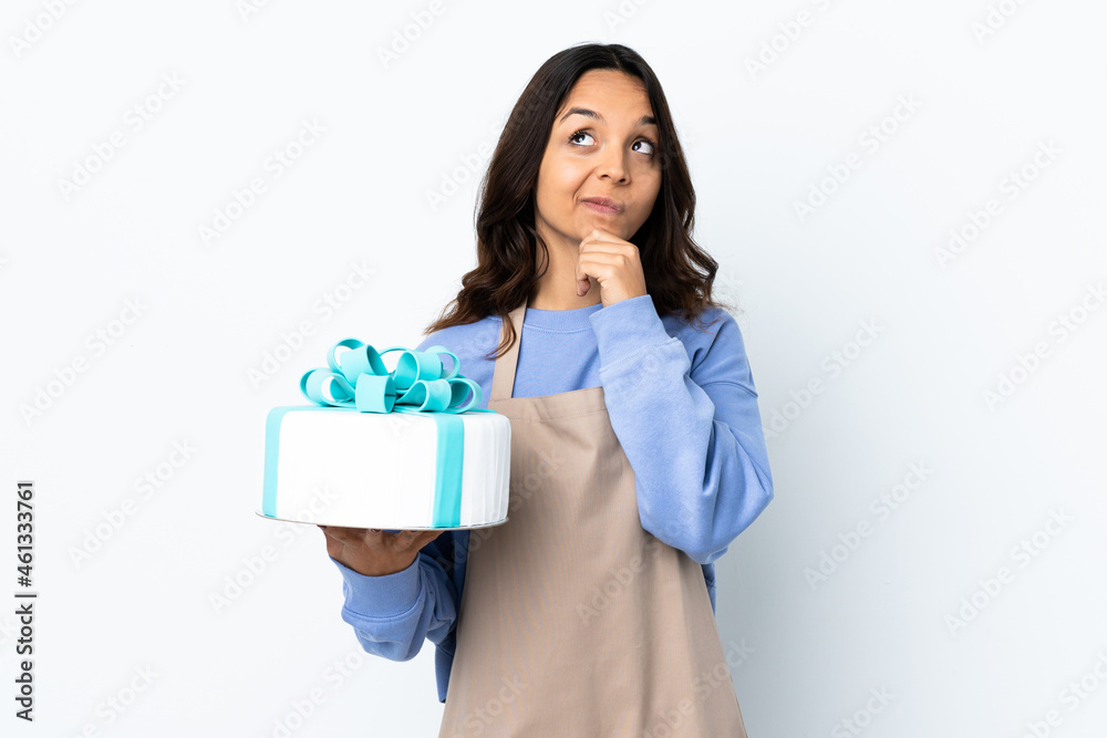 Pastry chef holding a big cake over isolated white background thinking an idea while looking up Pastry chef holding a big cake over isolated white background thinking an idea while looking up