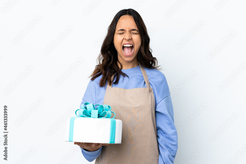 Pastry chef holding a big cake over isolated white background shouting to the front with mouth wide open Pastry chef holding a big cake over isolated white background shouting to the front with mouth wide open