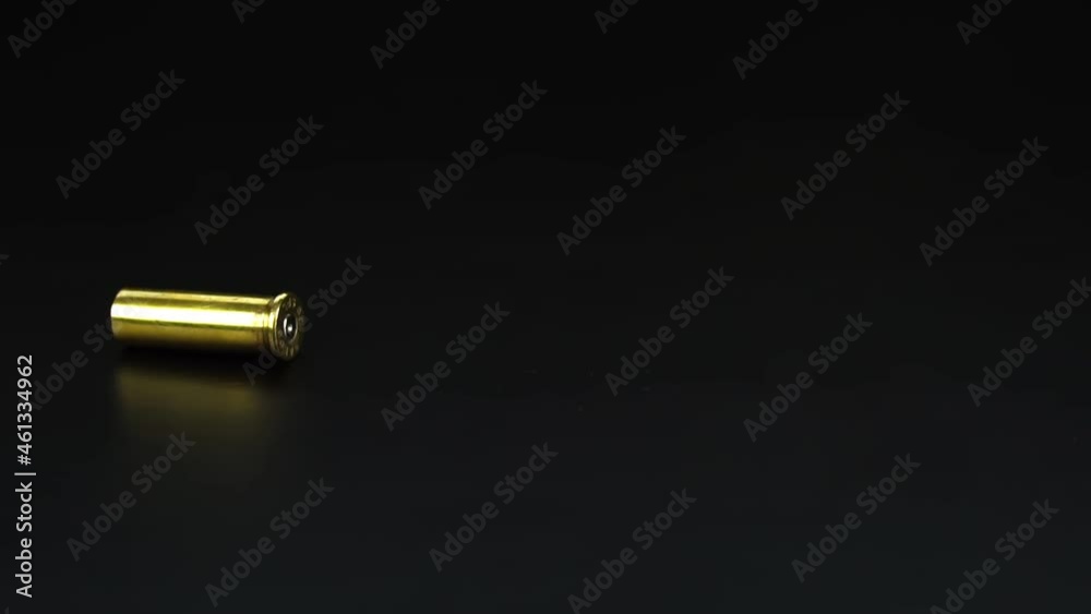 Bullet casings from a .38mm pistol falling closeup on black floor. Slow motion.