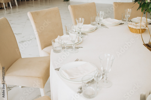 Wedding. Banquet. Chairs and a round table for guests, served with cutlery, flowers and utensils and covered with a tablecloth. Beige colors © Yuliia