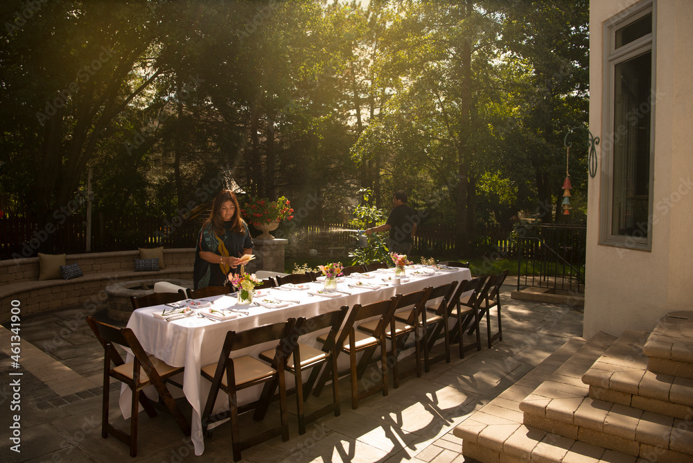 Woman setting table for an outdoor dinner party 