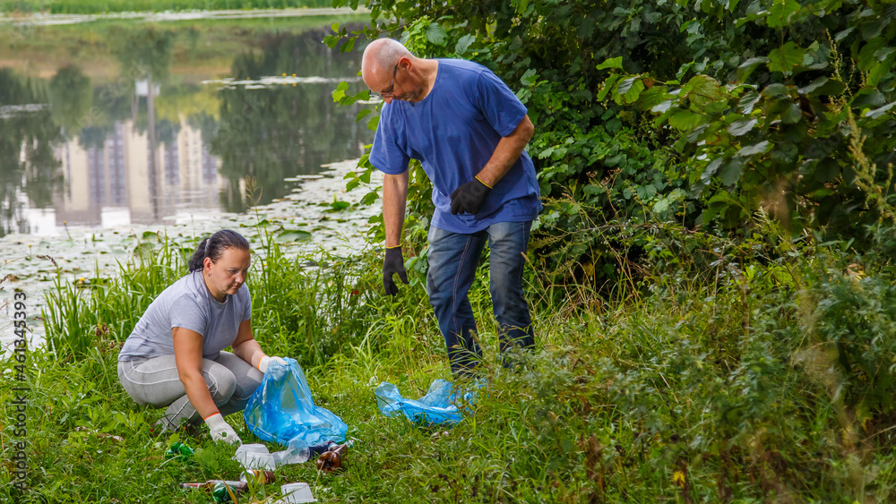Fototapeta premium A woman and a man volunteers clean up garbage from a landfill in the park.
