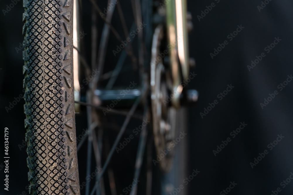 A black bicycle wheel with a tire close-up on a black background. Maintenance and repair of bicycles before responsible competitions. Bike workshop as a hobby or a small private business.