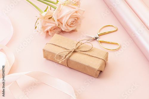 Gift box, roses and wrapping paper on pink background. Gifts for woman