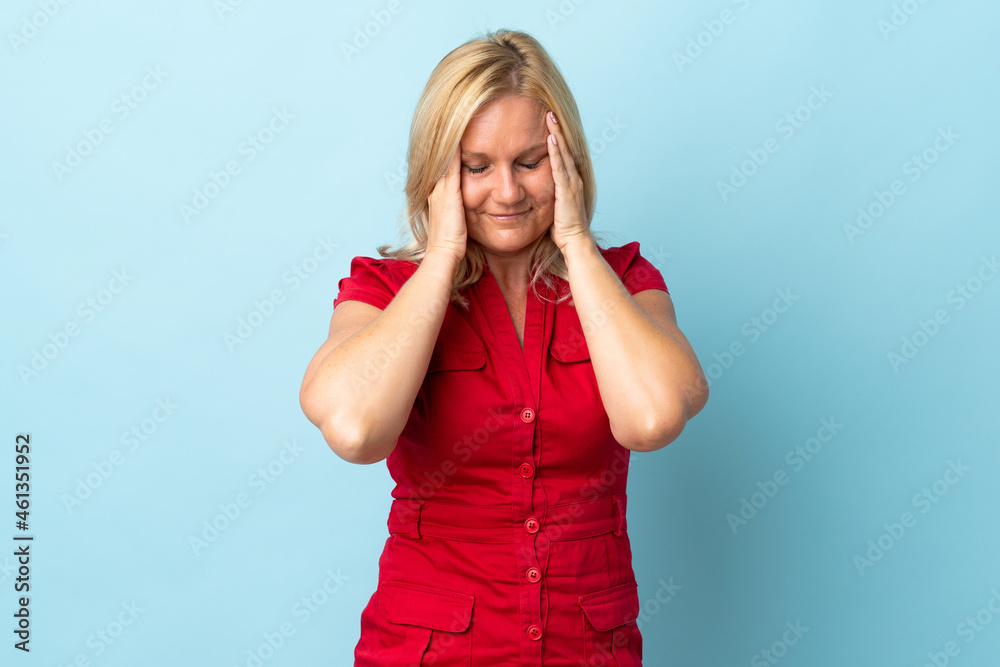 Middle age woman isolated on blue background with headache