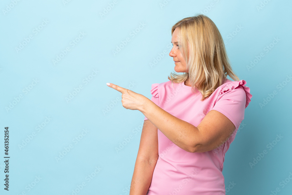 Middle age woman isolated on blue background pointing back Middle age woman isolated on blue background pointing back
