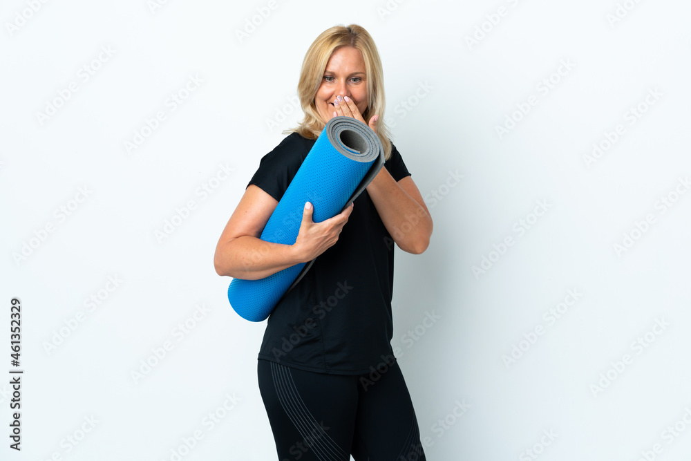 Middle age woman going to yoga classes while holding a mat isolated on white background with surprise and shocked facial expression Middle age woman going to yoga classes while holding a mat isolated on white background with surprise and shocked facial expression