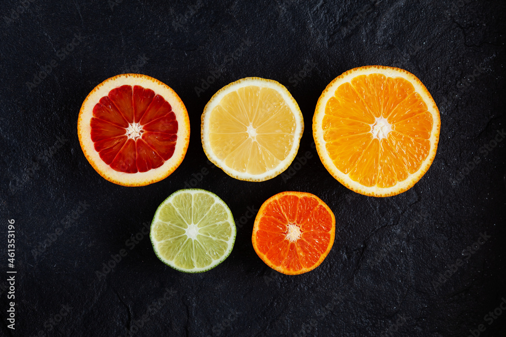 Citrus fruits (lemon, tangerine, lime, red orange) on dark stone background, top view Citrus fruits (lemon, tangerine, lime, red orange) on dark stone background, top view