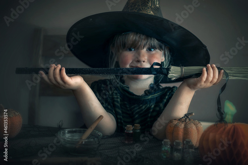 Little witch holding a broom in front of her