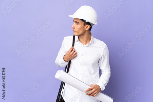 Young architect man isolated on background looking to the side