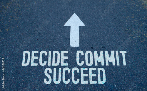 Business concept. On the asphalt road markings an arrow with the inscription - DECIDE COMMIT SUCCEED