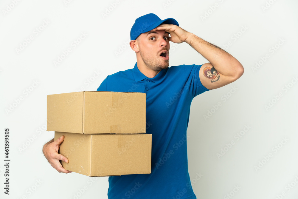 Delivery caucasian man isolated on white background doing surprise gesture while looking to the side Delivery caucasian man isolated on white background doing surprise gesture while looking to the side