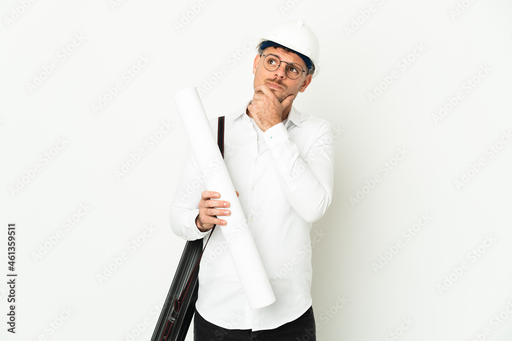 Young architect man with helmet and holding blueprints isolated on white background having doubts Young architect man with helmet and holding blueprints isolated on white background having doubts