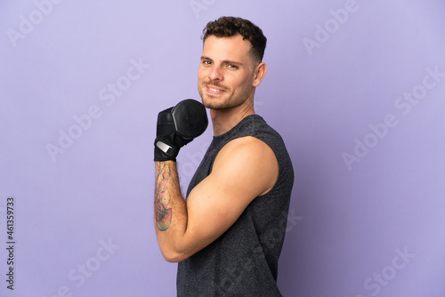 Young caucasian handsome man isolated on purple background making weightlifting