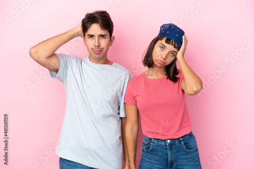 Young couple isolated on pink background with an expression of frustration and not understanding