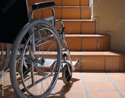 Empty wheelchair at the base of terracotta stairs photo